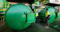 Engineers standing next to big green tanks 